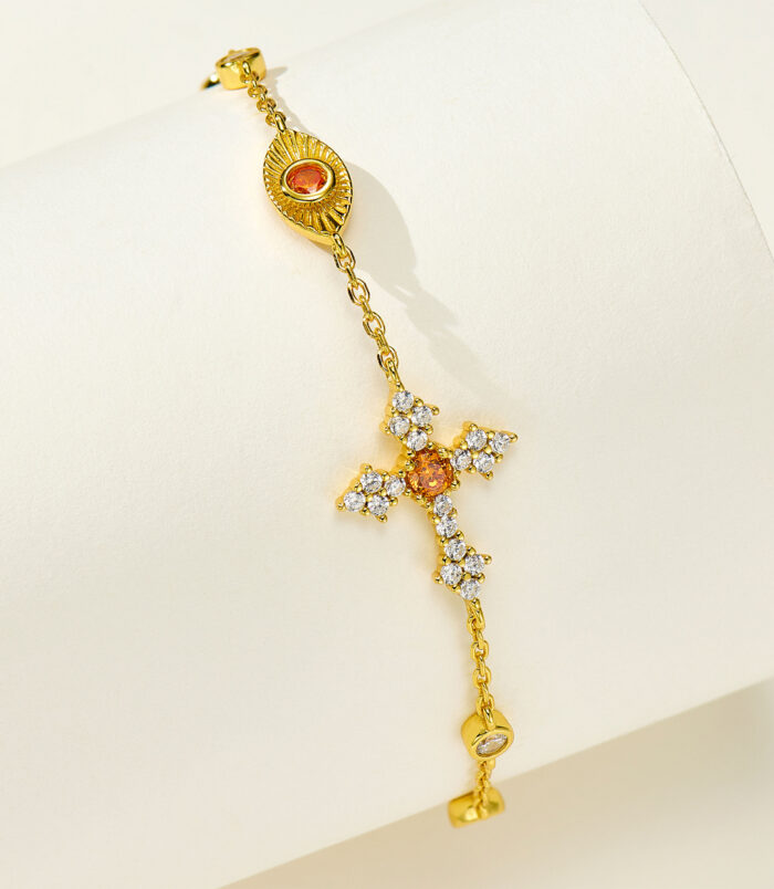 Side view of 18k gold plated 925 silver bracelet, plus a orange cross and eye shape cluster.
