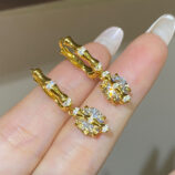 hand held close-up of Sterling silver with bamboo-shaped zirconia Huggie Hoop Earrings