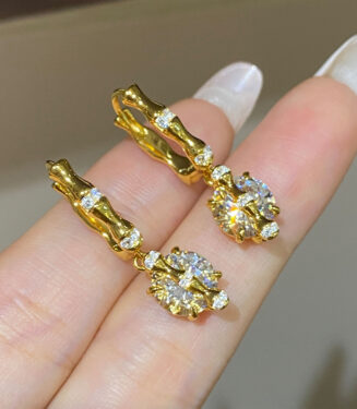 hand held close-up of Sterling silver with bamboo-shaped zirconia Huggie Hoop Earrings