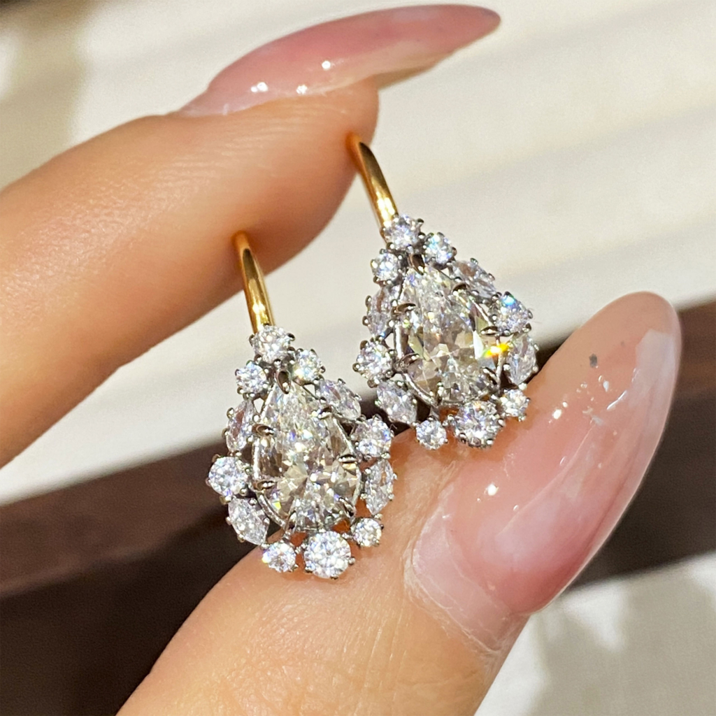 hand held close up of Sterling Silver Gold-Plated Pear-Cut Cubic Zirconia Drop Earrings