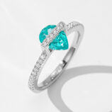 A striking sterling silver ring featuring a pear-shaped paraiba tourmaline as the centerpiece, complemented by sparkling diamond accents along the band.