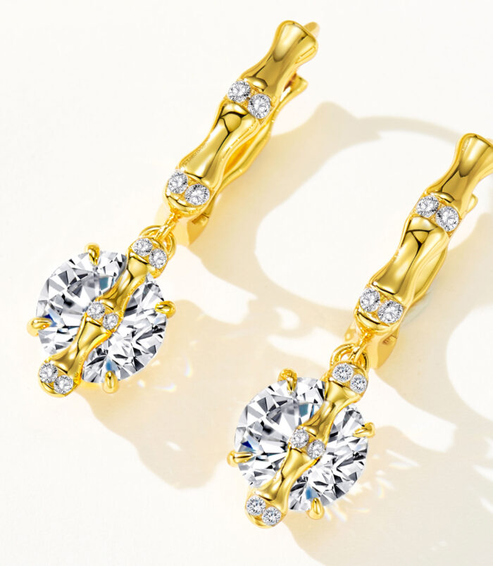 Sterling silver huggie hoop earrings with gold-plated finish, featuring a large round cubic zirconia center stone and smaller stones along the hoop.