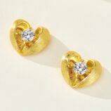 Sterling silver heart-shaped stud earrings with a brushed gold-plated finish, featuring a round clear cubic zirconia center stone.