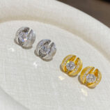 Set of gold and silver stud earrings with central round stones, displayed on a white fabric surface